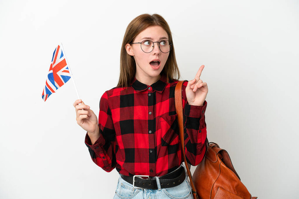 Junge Frau mit einer britischen Flagge auf blauem Hintergrund denkt an eine Idee, die den Finger nach oben zeigt - Foto, Bild