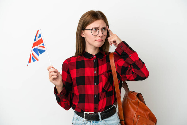 Junge Frau mit einer Flagge des Vereinigten Königreichs auf blauem Hintergrund hat Zweifel und denkt nach - Foto, Bild
