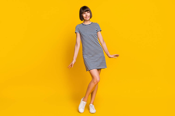 Full length photo of cute brunette millennial lady wear striped dress isolated on yellow background. - Foto, Imagen