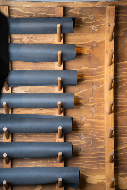 A vertical shot of yoga mats on wooden hangers - Фото, зображення