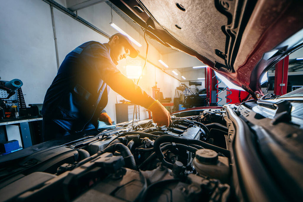 Jovem mecânico verificando o nível de óleo do motor no carro. Auto centro de serviço de reparação automóvel.  - Foto, Imagem