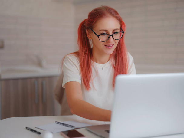 miellyttävä onnellinen nuori nainen freelancer työskentelee tietokoneella kotona. Houkutteleva nainen opiskelee verkossa kannettavan tietokoneen ohjelmiston, web surfing tietoa tai verkkokaupoissa. - Valokuva, kuva