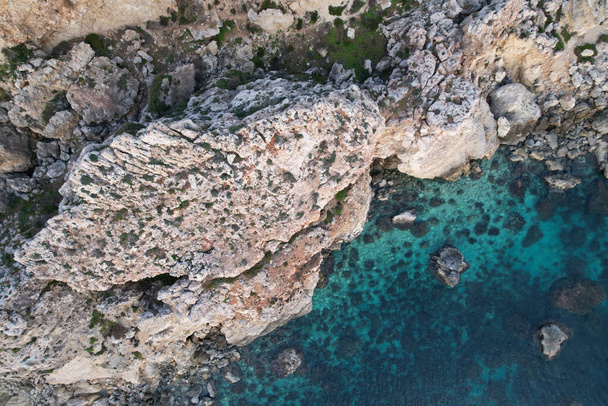 A top view of a blue ocean and a rocky cliff in daylight - Фото, зображення
