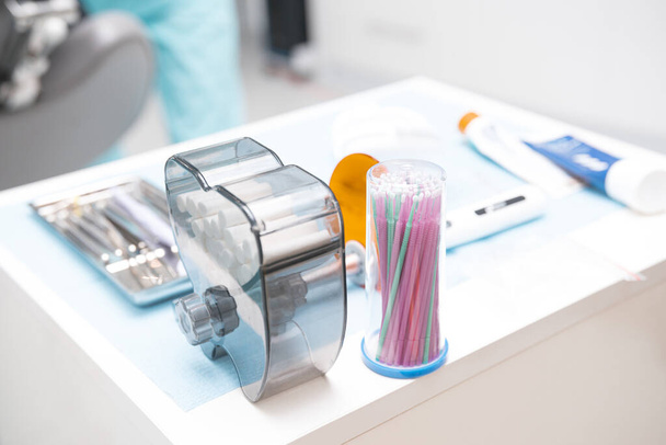 Закрыть фотографию стоматологических инструментов и белых ватных рулонов на подносе в шкафу. - Фото, изображение