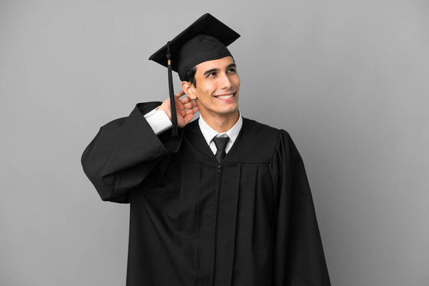Młody argentyński absolwent uniwersytetu odizolowany na szarym tle myśląc o pomyśle - Zdjęcie, obraz