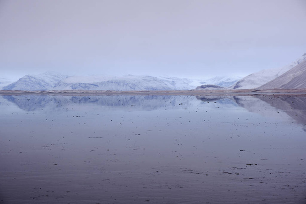 Thin strip of land viewed across reflective water. Muted colors give a calm, ethereal atmosphere - Foto, Bild