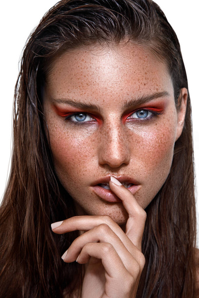 A studio shot of Caucasian woman with brunette hair and freckles on face posing with finger on lips - Foto, Bild