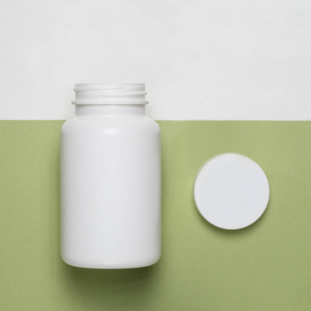 Empty plastic jar with lid on a green background - Fotoğraf, Görsel