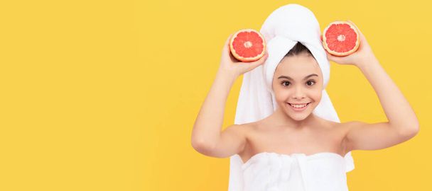 веселый ребенок в полотенце с грейпфрутом на желтом фоне. Косметика и уход за кожей для подростка, дизайн плакатов. Баннер с изображением девушки-красавицы - Фото, изображение