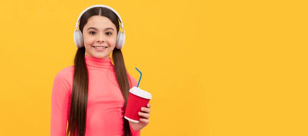 Hezký den. dospívající dívka pije čaj a poslouchá hudbu. Šťastné dítě pije kakao. Horizontální plakát izolované dětské tváře, záhlaví banneru, kopírovací prostor - Fotografie, Obrázek