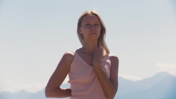 Die erwachsene, temperamentvolle Frau steht mit den Händen hinter dem Rücken vor dem Hintergrund der Berge. Mittelschuss - Filmmaterial, Video