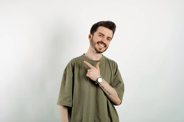 Cheerful caucasian man wearing casual clothes posing isolated over white background smiling man pointing left with index finger and looking at the camera. - Foto, immagini