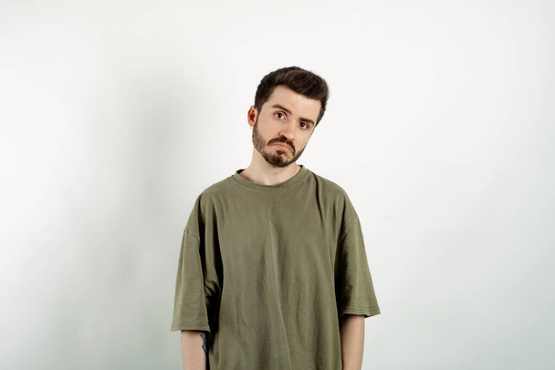 Handsome caucasian man wearing khaki t-shirt posing isolated over white background crying wipes tears losing his job. I don't know. - Fotografie, Obrázek