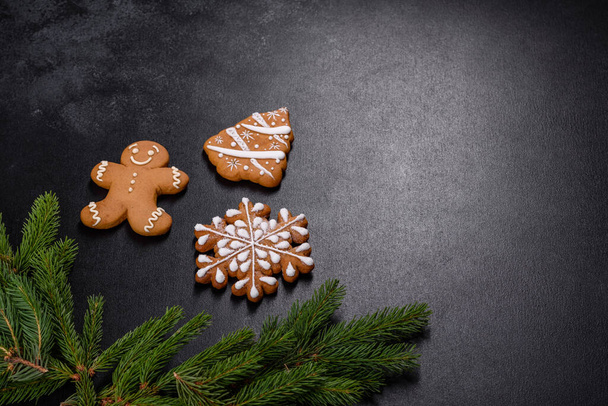 Hermoso pan de jengibre delicioso con ramas de árbol de Navidad sobre un fondo de hormigón oscuro. Preparación de decoraciones para la mesa de Navidad - Foto, imagen
