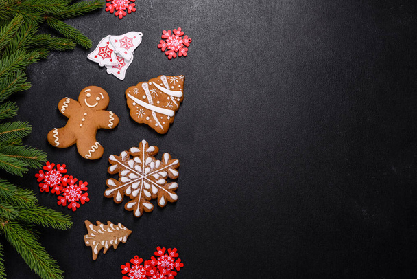 Beautiful delicious gingerbread gingerbread with Christmas tree branches on a dark concrete background. Preparing decorations for the Christmas table - Photo, Image