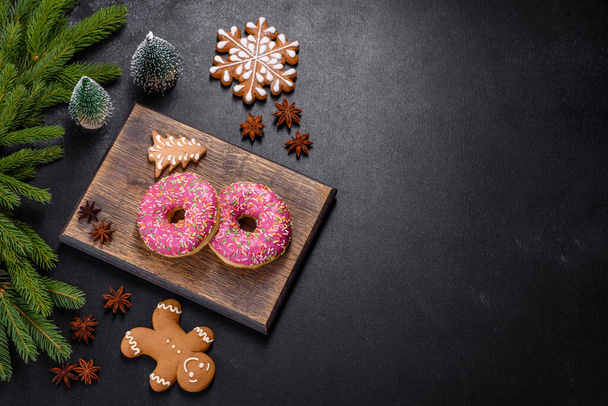 Ein wunderschöner Donut mit rosa Glasur und farbigem Streusel auf dunklem Betongrund. Süßigkeiten auf den Weihnachtstisch - Foto, Bild