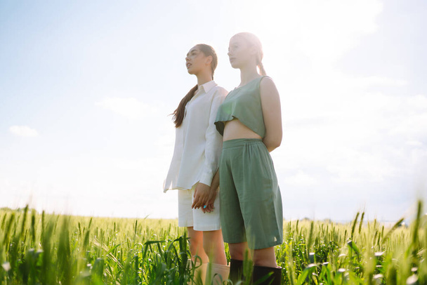 Two fashion woman in the green field. Freedom travel. Summer landscape. - Фото, изображение