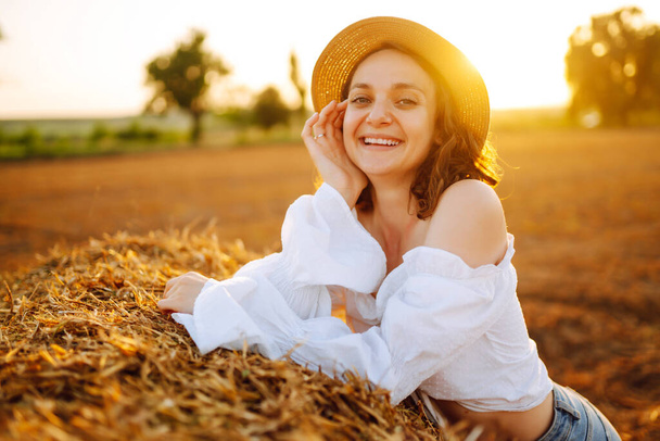 Happy woman near haystack at sunset. Fashion concept. Nature, vacation, relax and lifestyle.  - 写真・画像