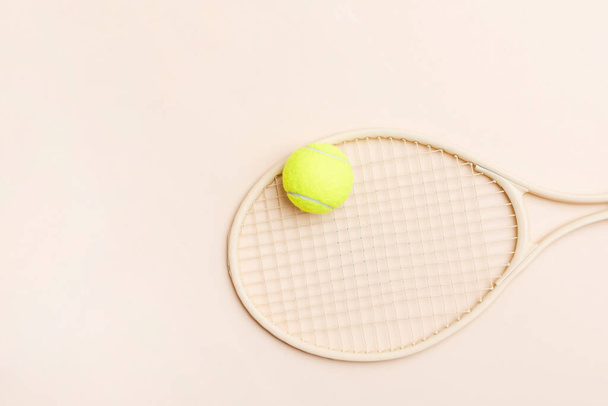 Beige tennis racket and yellow ball on beige background. Horizontal sport theme poster, greeting cards, headers, website and ap - Photo, image