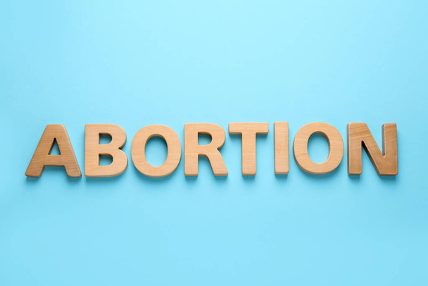 Word Abortion made of wooden letters on light blue background, flat lay - Foto, Imagem