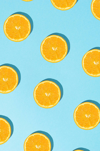 Creative summer pattern with sliced fresh orange on sunny blue background. Flat lay. - Photo, Image