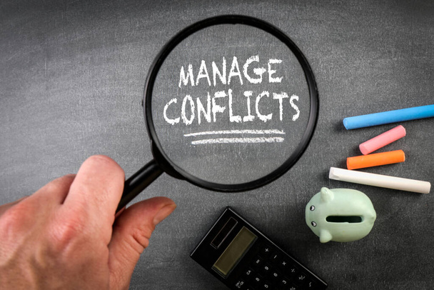 MANAGE CONFLICTS. Text and magnifying glass on a blackboard. - Photo, Image