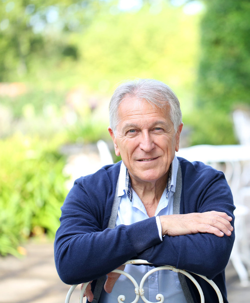 Senior man sitting in home garden - Foto, imagen