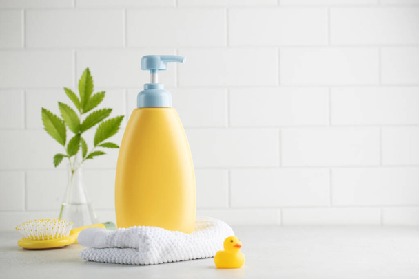 Yellow bottle of children cosmetic product toy rubber duck and toiletries in bathroom. Safe cosmetics for sensitive baby skin. Mock-up for design - Photo, image