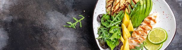 Buddha bowl, Grilled chicken breast, halloumi, pineapple, avocado, green rocket salad, lime and olive oil. healthy and balanced food. Long banner format. top view. - Photo, Image