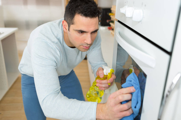 man earnestly cleaning oven in home - Photo, Image