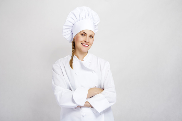 A young, female chef in a traditional hat and coat. - Foto, afbeelding