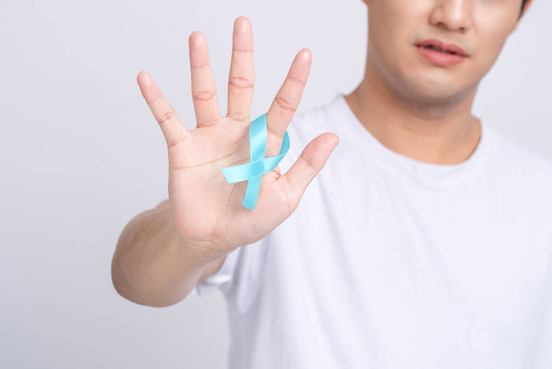 Визнання раку простати. Крупним планом людська рука тримає синю стрічку світла для підтримки життя і хвороб. Всесвітній день здоров'я та раку чоловіків
 - Фото, зображення