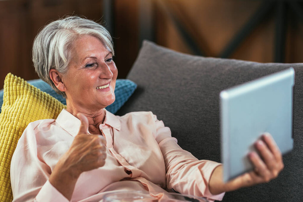 Mujer mayor feliz celebración de videoconferencia tableta digital llamada por distancia social - Foto, Imagen