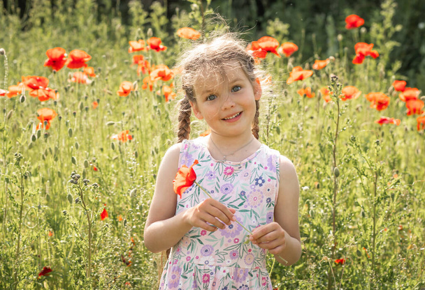 Kaunis pieni tyttö pellolla unikonkukkia, kesätunnelmaa, iloinen lapsi, aurinkoinen päivä. - Valokuva, kuva