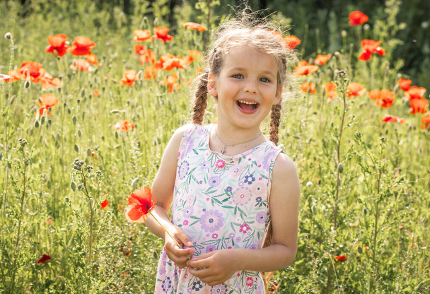 Kaunis pieni tyttö pellolla unikonkukkia, kesätunnelmaa, iloinen lapsi, aurinkoinen päivä. - Valokuva, kuva