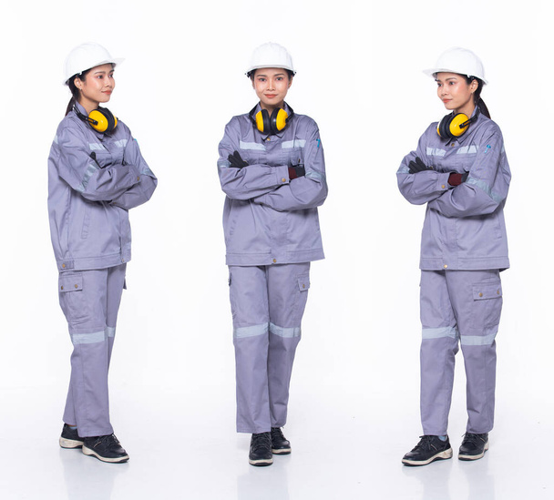 Full length 30s Ασιάτισσα μηχανικός ηλεκτρολόγος μηχανικός, σταυρός χέρια σίγουροι, φορούν στολή εργαλείων ασφαλείας. Μαύρο μαλλί Εργοστάσιο θηλυκό αισθάνονται ευτυχείς χαμόγελο ευεξία πάνω από λευκό φόντο απομονωμένο - Φωτογραφία, εικόνα