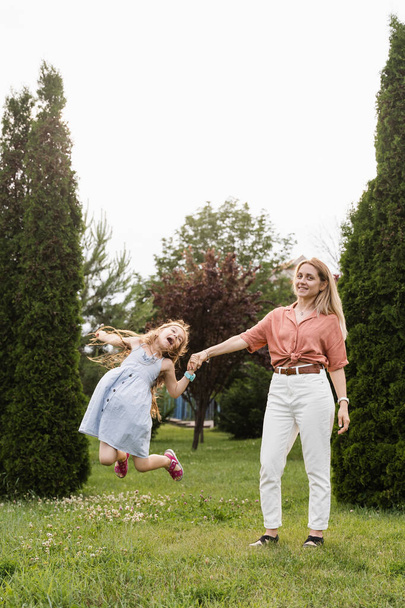 Mom and daughter having fun together. Happy family lifestyle. Daughter jumping, smiling and laughing. Love in family - Foto, afbeelding