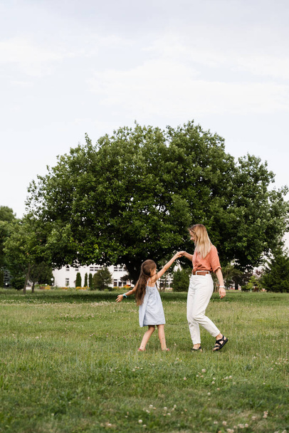 Mama i córka spacerują i bawią się razem w parku. Szczęśliwego życia rodzinnego. Miłość w rodzinie. Szczęście matki i jej dziecka - Zdjęcie, obraz