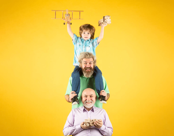 Fathers day concept. Three different generations ages grandfather father and child son playing with toy plane in studio. Journey travel trip concept. Isolated background - Photo, Image
