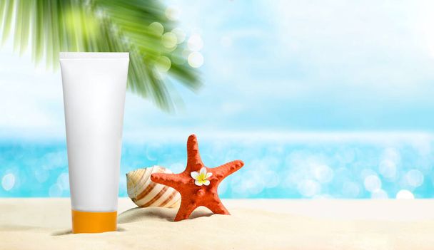 Weiße leere Kosmetikröhre mit Sonnencreme, Sonnencreme für den Körper. Palmenzweige und Seesterne und Muscheln am Sandstrand. Hautpflege für Sommer und Reise-Attrappe - Foto, Bild