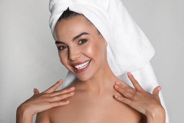 Beautiful young woman with towel on head against light background - Foto, afbeelding