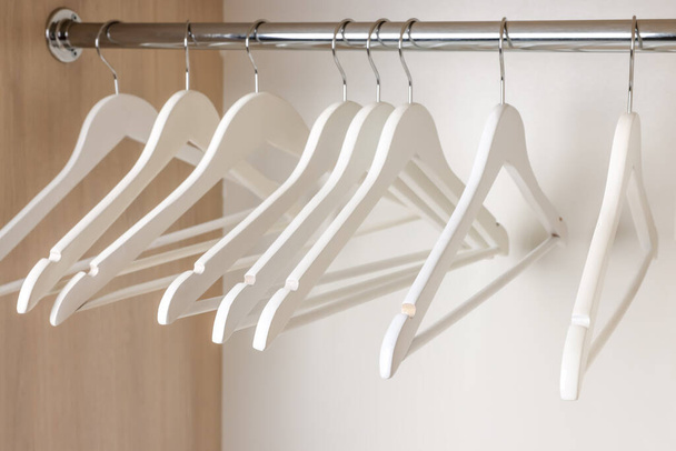 Set of wooden clothes hangers on wardrobe rail, closeup - 写真・画像