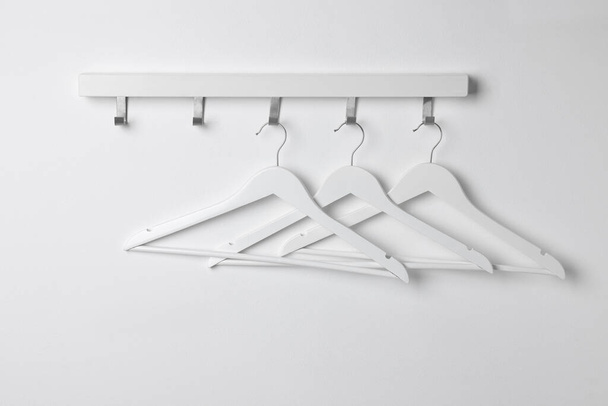 Rack with empty clothes hangers on white wall - Φωτογραφία, εικόνα