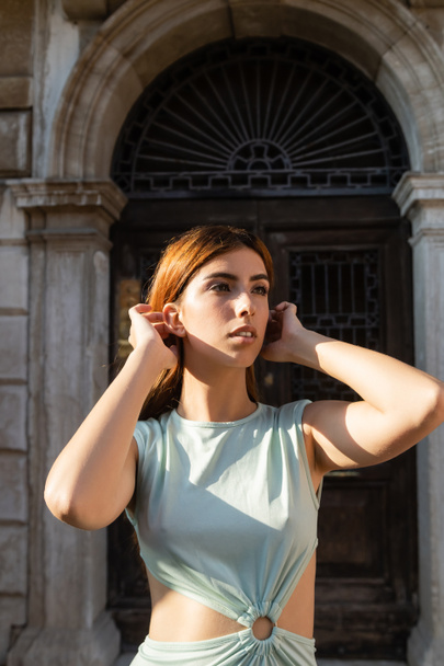 csinos nő rögzítő haj, miközben néz el a elmosódott utcán Velence - Fotó, kép