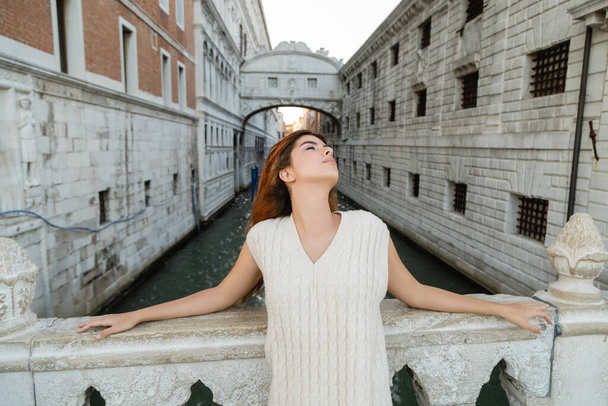 junge Frau mit geschlossenen Augen in der Nähe der Seufzerbrücke und des mittelalterlichen Gefängnisses in Venedig - Foto, Bild