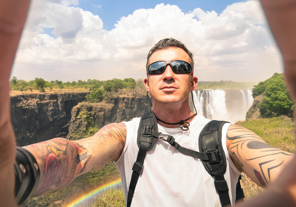 Moderno hipster jovem tomando uma selfie em Victoria Cachoeiras - Estilo de vida de viagem de aventura desfrutando de momento de conexão com a natureza - Viagem excursão em África Zimbabué natureza maravilha destino
 - Foto, Imagem