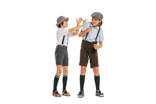 Friends. Two school age boys, stylish kids wearing retro clothes isolated over white background. Concept of childhood, vintage summer fashion style. Copy space for ad - Φωτογραφία, εικόνα