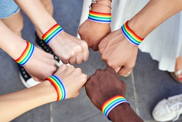 Gruppe multiethnischer Menschen, die Hände mit Armbändern der LGBT-Regenbogenfahne zusammenlegen. Vielfalt, Stolz, Gleichheit und Einheit. - Foto, Bild