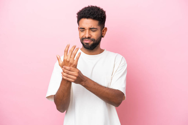 Young Brazilian man isolated on pink background suffering from pain in hands - Photo, Image