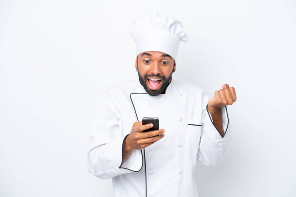 Giovane chef brasiliano isolato su sfondo bianco sorpreso e l'invio di un messaggio - Foto, immagini